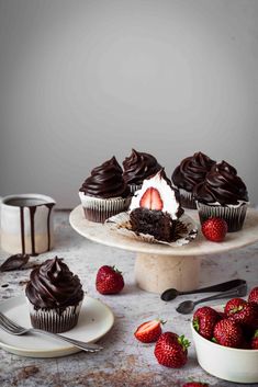 cupcakes with chocolate frosting and strawberries on the side next to them