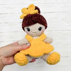 a hand holding a small stuffed animal with a yellow star on it's chest