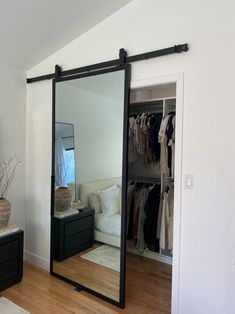 a large mirror sitting on top of a wooden floor next to a dresser and bed