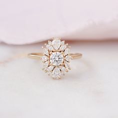 a close up of a diamond ring on a white surface with a pink cloth in the background