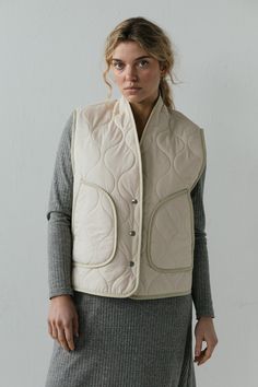 The Anouk Vest is pure comfort and warmth. This quilted vest features a snap front closure and roomy front pockets. The textile is lined with warm and cozy sherpa fleece. Cut roomy for all kinds of layering possibilities. Oversized fit. Model is wearing X SMALL. Model is 5'8". Please review our size guide prior to ordering. Need specific measurements? Send us an email and we will be happy to help you find the perfect fit. Everyday Cotton Vest Outerwear, Winter Quilted Cotton Vest, Beige Vest For Layering, Beige Cotton Vest Outerwear, Everyday Beige Winter Vest, Spring Layers, Quilted Vest, Sherpa Fleece, Oversized Fits