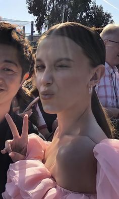 two people posing for the camera with one holding up her peace sign in front of them