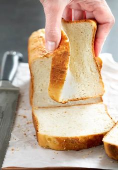 a person holding a loaf of bread with one slice cut off and another half eaten