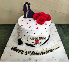 a white cake with red roses on top and black lettering that says happy 25th anniversary