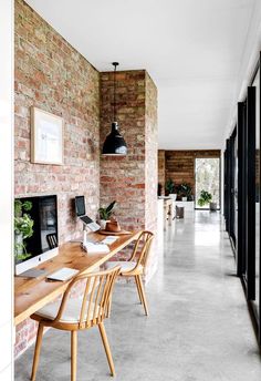 an image of a room with brick walls and wooden furniture on the floor, along with large windows