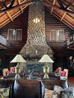 a living room with couches, lamps and a stone fireplace in the middle of it