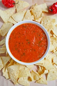 a white bowl filled with salsa surrounded by tortilla chips