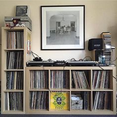 a record player sitting on top of a wooden shelf filled with vinyl records and cds