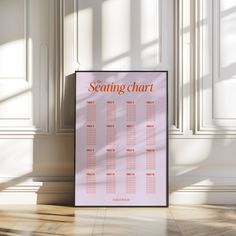 a pink seating chart sitting on top of a wooden floor next to a white wall