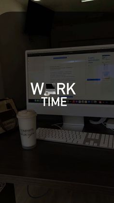 a desktop computer sitting on top of a wooden desk next to a cup of coffee