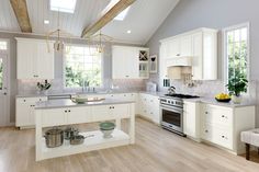 a large kitchen with white cabinets and wood flooring, along with an island in the middle