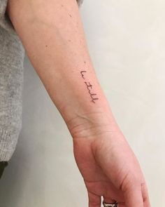 a person with a small tattoo on their left wrist and the word faith written in cursive font