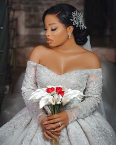 a woman in a wedding dress with flowers on her lap and wearing a tiara