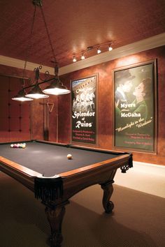 a pool table in a room with posters on the wall