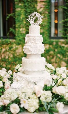 a wedding cake sitting on top of a table next to white flowers and greenery