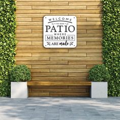 a welcome sign is placed on the side of a building with plants growing around it