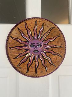 a sun painted on the side of a door with purple and orange designs in it