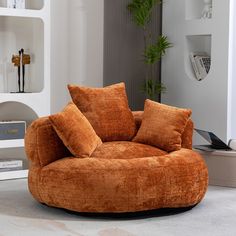 a living room with a large orange chair and bookshelf in the back ground