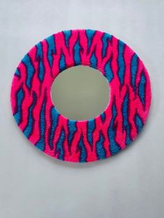 a pink and blue animal print mirror sitting on top of a white table next to a wall