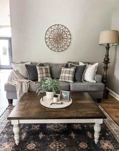 a living room with a couch, coffee table and rug on the floor in front of it