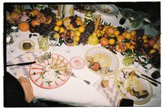 a table full of food and plates with utensils on it, including oranges