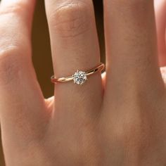 a woman's hand with a diamond ring on top of her finger, showing the center stone