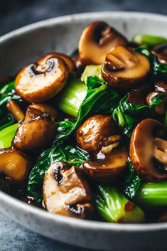 a white bowl filled with mushrooms and broccoli on top of a blue table