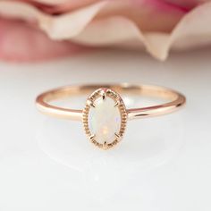 a white opalite ring sitting on top of a table next to a pink rose