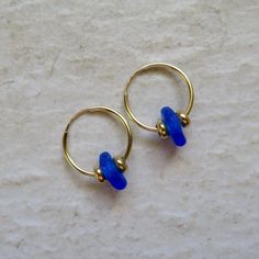 Seaglass Hoop Earrings~ These cute small endless hoops have blue seaglass and gold beads, great gift for the beach lover. Hoops 16mm. *This listing is for the earrings in the first photo ready to ship **video shows 20 and 24mm. hoops Shop~ http://www.etsy.com/shop/HanaMauiCreations?ref=pr_shop_more International buyers please read our shipping policies before ordering~ POLICIES~ https://www.etsy.com/shop/HanaMauiCreations/policy?ref=shopinfo_policies_leftnav Blue Hoop Jewelry For The Beach, Blue Small Hoop Jewelry For The Beach, Blue Small Hoop Jewelry For Beach, Glass Hoop Earrings For Gift, Glass Hoop Earrings As Gift, Beach Jewelry With Tiny Beads, Adjustable Blue Hoop Earrings For Beach, Adjustable Small Hoop Jewelry For Beach, Nickel-free Blue Hoop Earrings For The Beach