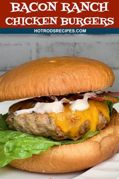 a bacon ranch chicken burger on a bun with lettuce and cheese, sitting on a white plate