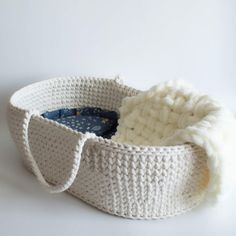 a white knitted basket with a button on the front and bottom, sitting on a white surface