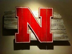 a wooden sign with the letter n painted on it's side in front of a wall