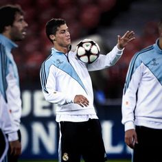 a man holding a soccer ball in his right hand while standing next to other men