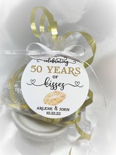 an ornament for a 50th wedding anniversary with gold lipstick on it and ribbon