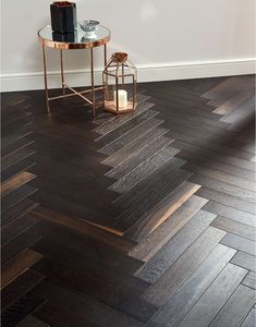 a table with a candle on top of it next to a wood flooring pattern