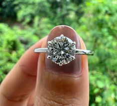 a close up of a person's hand holding a ring with a diamond in it