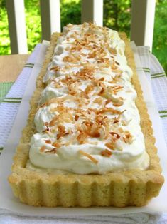 there is a long cake on the table with white frosting and toasted coconuts