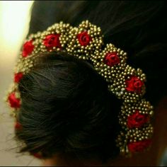 a close up of a woman's head wearing a gold and red hair piece