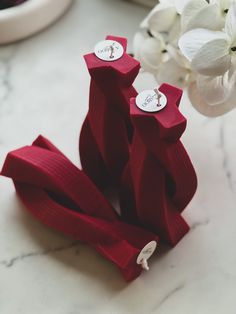 two red ribbons are sitting on a table next to some flowers and a vase with white orchids