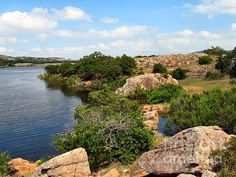 a lake surrounded by rocks and trees on a sunny day