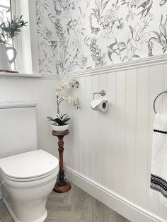 a white toilet sitting in a bathroom next to a wall with flowers on the side