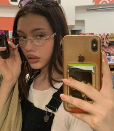 a woman wearing glasses is looking at her cell phone while holding it up to her face