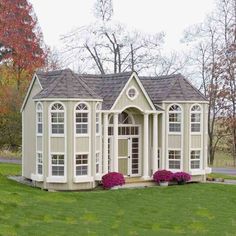 a small house with windows and flowers in the front yard