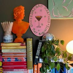 a shelf with books, plants and a busturifit on top of it