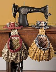 an old sewing machine sitting on top of a wooden table next to three different hats