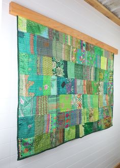 a wall hanging made out of patchwork and wooden planks in a room with white walls