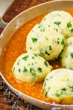 several balls of food in a pan on a wooden table with spoons and utensils