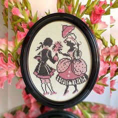 a cross stitch picture with pink flowers in the background