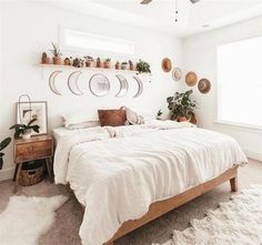 a bedroom with white walls and lots of potted plants on the shelves above the bed