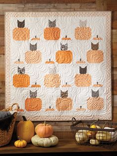 a quilted wall hanging with pumpkins and gourds in front of it